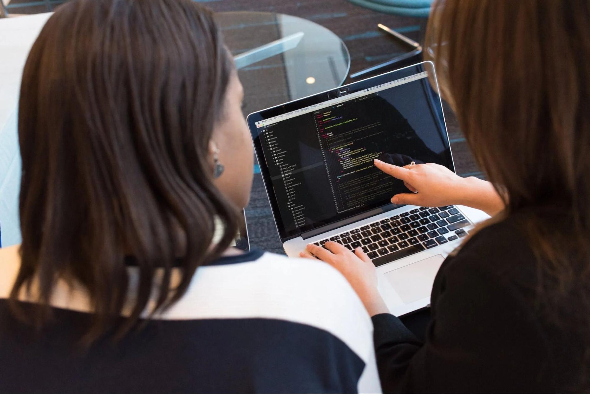 Two developers looking at a screen collaborating on a piece of code