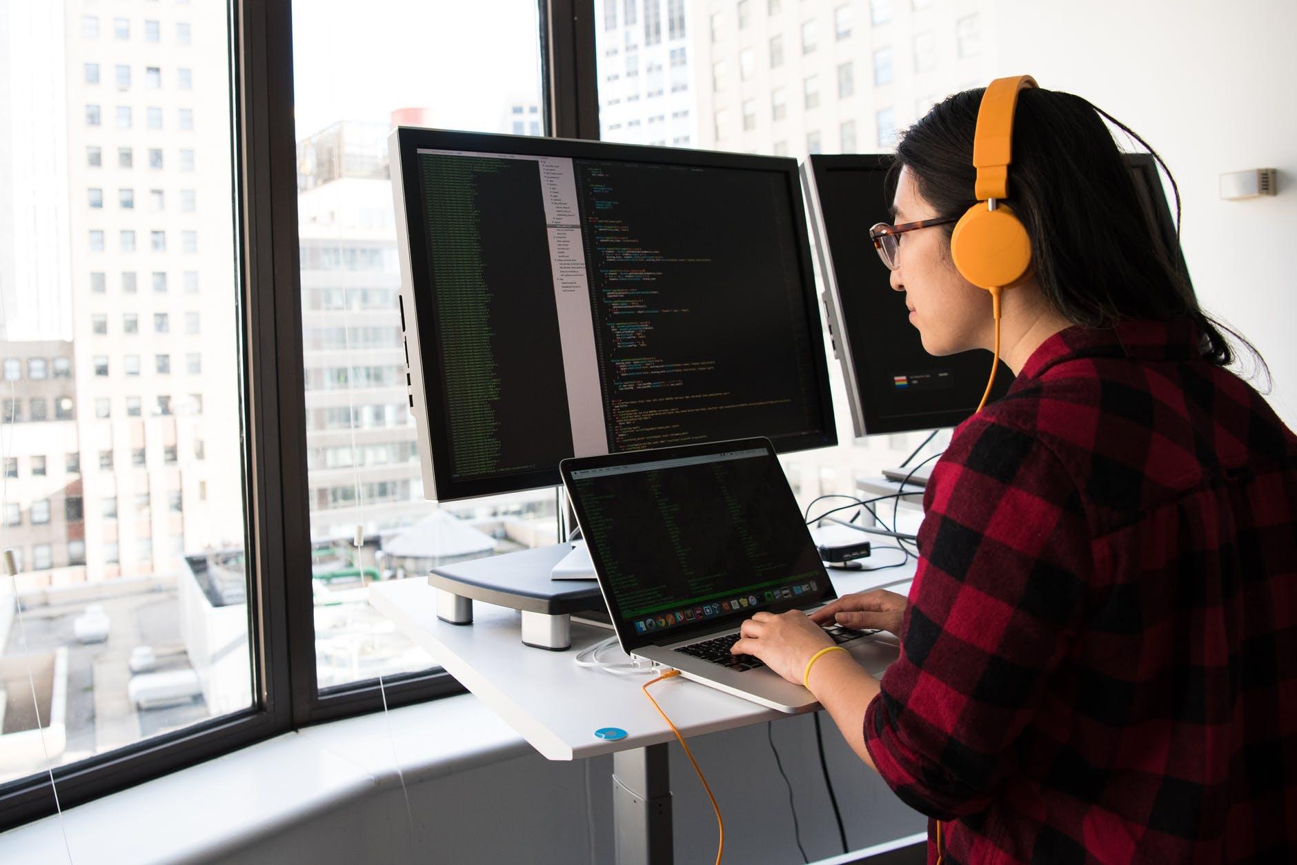 01- Person working from team augmentation on developing software with multiple screens